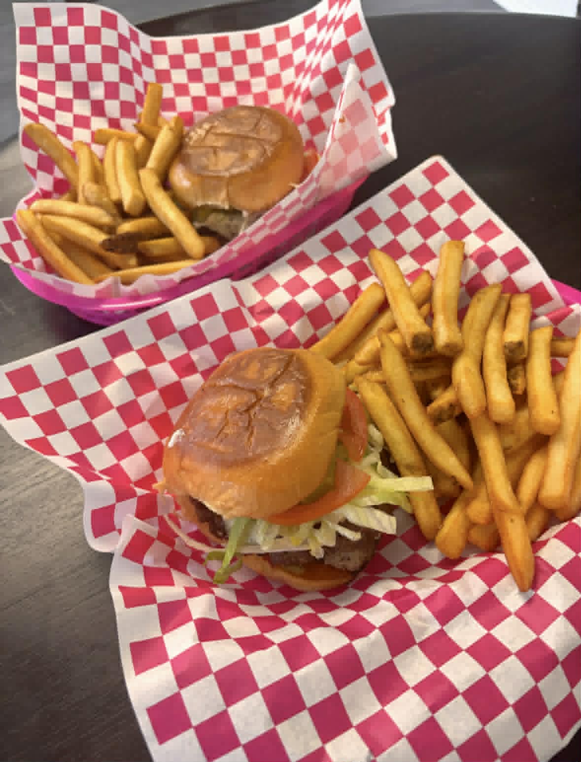 Two smash burgers with fries in signature pink baskets
